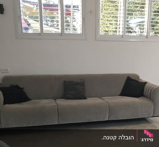 ספה אפורה עם כריות בחדר מואר